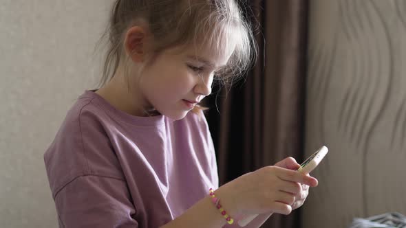 a Little Girl is Engaged Online in the Application on the Phone