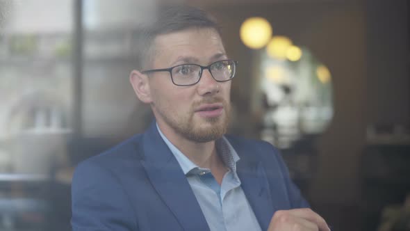 Close-up of Confident Caucasian Businessman in Eyeglasses Talking To Unknown Person. Portrait of