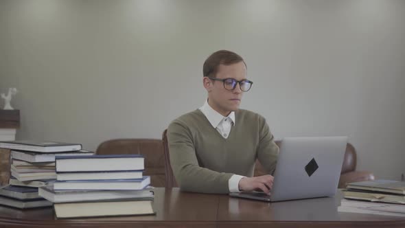 Portrait Adorable Man in Glasses Sitting at the Wooden Table in the Office