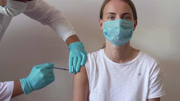 Woman and Her Doctor Wearing Face Masks and Getting a Vaccine Shot in a Doctor's Office