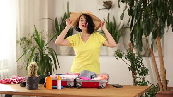Happy Woman in Hat Dancing Packing Suitcase Getting Ready for Summer Vacation