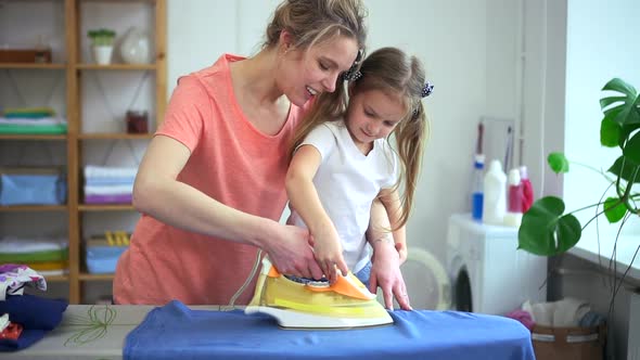 Woman Show Young Girl How to Iron Clothes on Board