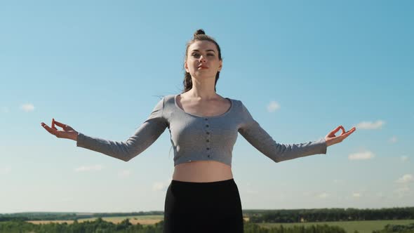 Slender Woman in Gray Top and Black Sports Shorts Practices Yoga Outdoors in Nature