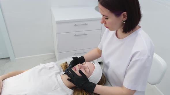 Cosmetologist Applies a Woman a Therapeutic Mask on Her Face