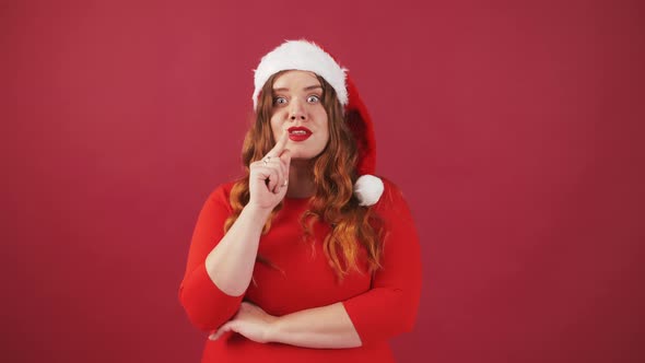 Pensive Young Plus Size Woman in Santa Hat Raising Index Finger Up with Great New Christmas Red