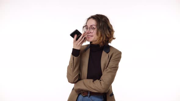 Beautiful Brunette Woman in Stylish Casual Clothes and Glasses Records a Voice Message on Her Mobile