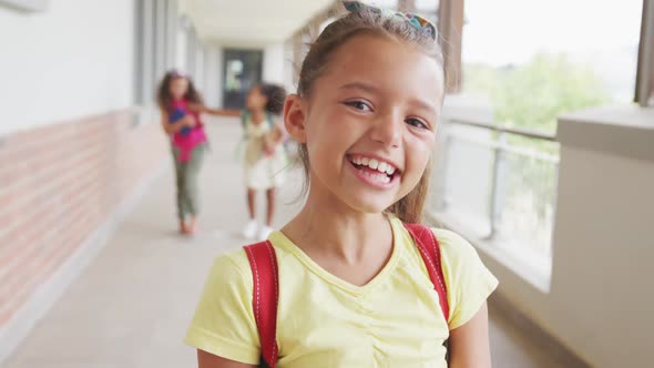 Video of happy caucasian girl standing on school corridor