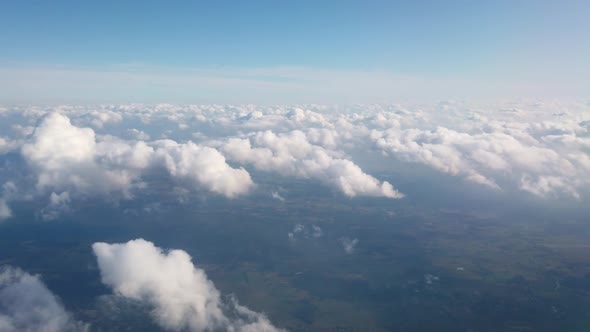 Beautiful Aerial View at Land and White Fluffy Clouds Through Window of Flying Plane.