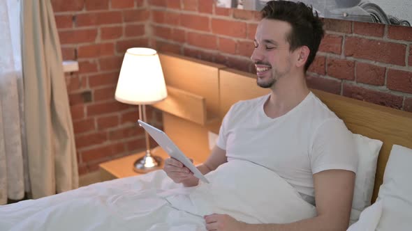 Young Man Doing Video Chat on Tablet in Bed