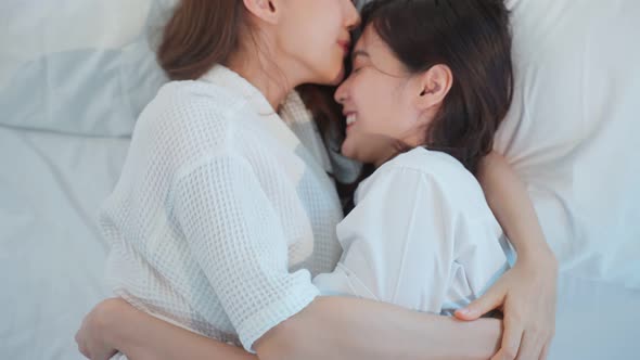 Asian beautiful lesbian couple lying down on bed and kiss on forehead.