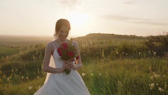 Smiling Woman in White Dress Holds Her Flowers
