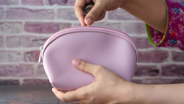 Close Up of Women Hand Saving Coins in a Wallet 