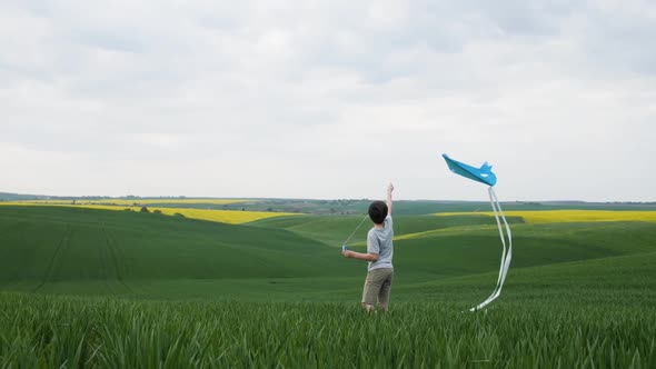 A Boy in a Field Tries to Launch a Kite