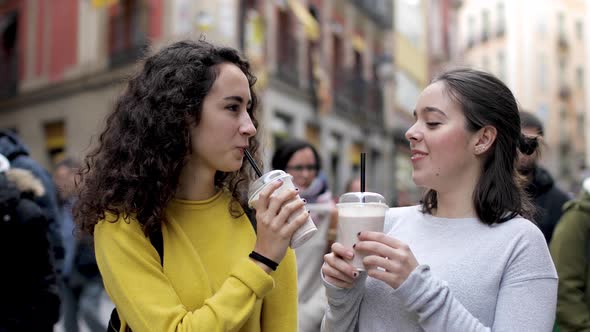 Two happy girls in Madrid drinking a milkshake