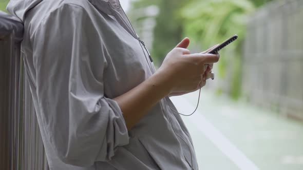 Young Asian woman fitness runner using mobile phone listening music at a public park.