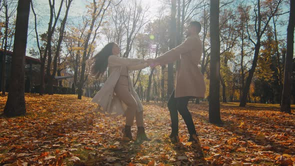 Positive Couple Spinning Holds Hands in Autumn Park Young Guy and Girl Enjoy Romantic Date in Sunny