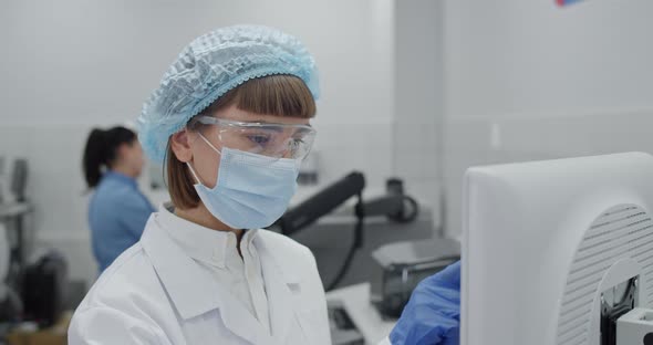 Crop View of Female Medical Worker in Protective Mask and Googles Entering Data on Computer