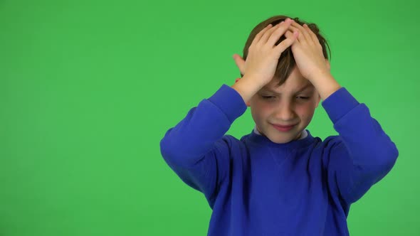 A Young Cute Boy Hears a Piercing Noise, Frowns and Covers His Ears - Green Screen Studio