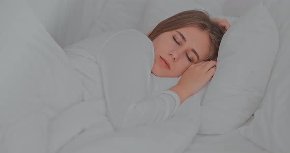 Beautiful Girl Lies Under a White Blanket in the Bedroom and Sleeps Soundly