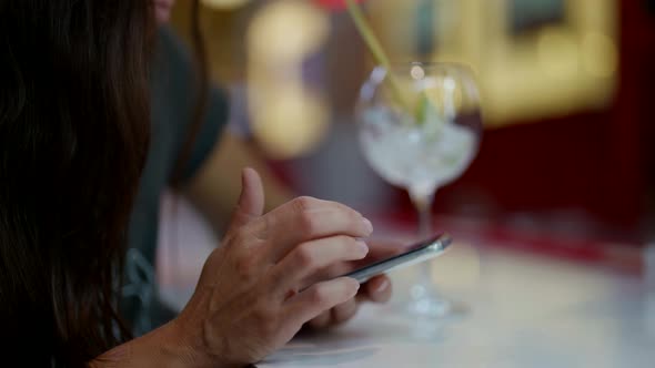 Lady in Bar Drinking Cocktails and Using Smartphone with Social Networking and Application