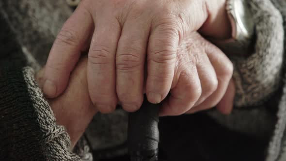 wrinkled old man' hands crossed on the stick