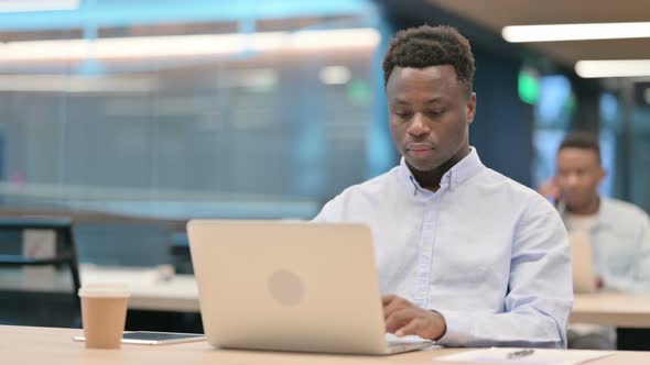 African Businessman Feeling Shocked While Using Laptop in Office