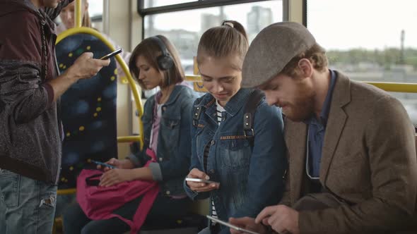 Young Man and Woman Chatting about Gadgets in Bus