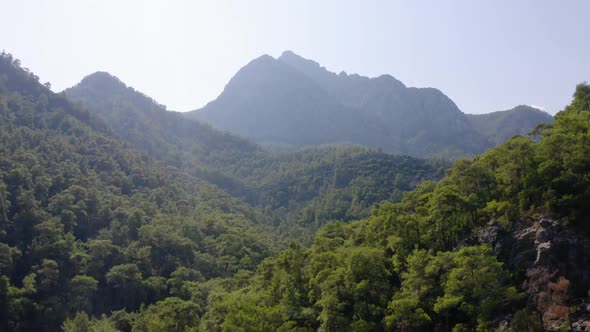 Mountains Peaks Overgrown with Green Dense Forests Against Blue Sky