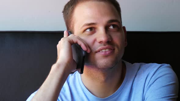 Young and Healthy Man Smiling and Talking on Smart Phone at Home.