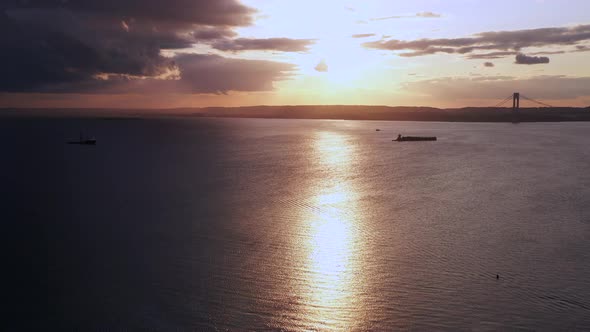drone camera pan right over Coney Island Creek viewing a dark golden, cloudy sunset while revealing