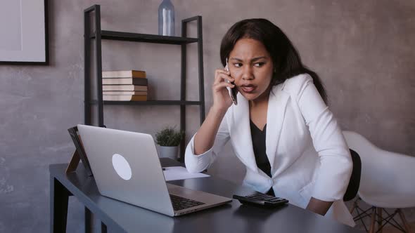 Smiling Young African American Businesswoman Working on a Laptop at Her Desk in a Bright Office