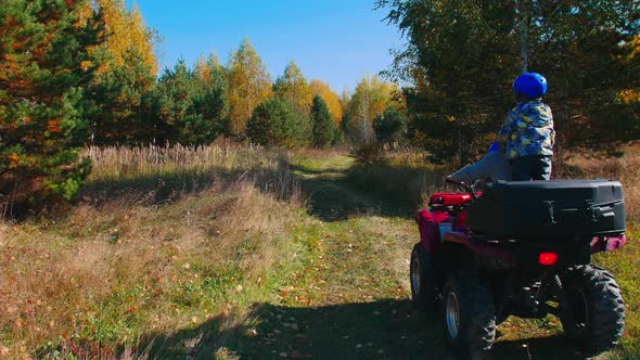 Family with Little Kid Rides Quad Bikes in the Woods