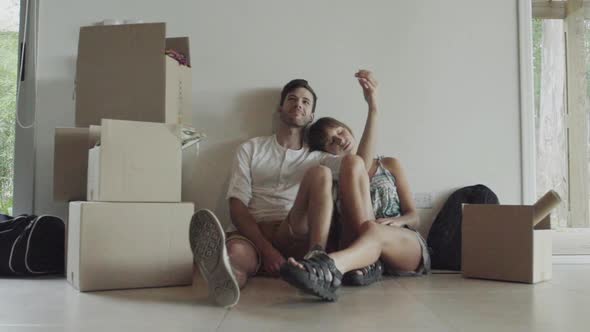 Couple sitting on floor amongst cardboard boxes