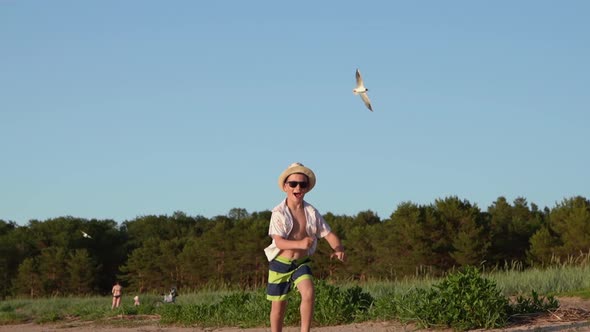 a Funny Boy in Shorts and a Hat Runs Merrily Along a Sandy Beach