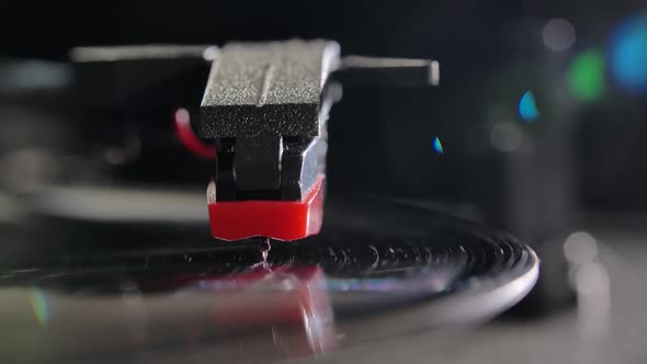 Front View Vinyl Record Spins on a DJ Turntable. Close Up of a Needle and a Black Record Illuminated