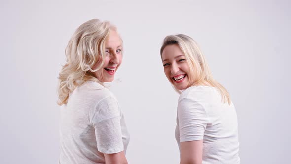 Two Joyful Caucasian Women Turning Around at the Camera and Smiling Medium Closeup Isolated on White