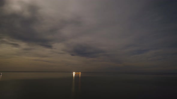 Time lapse of the moon setting over water with moving stars and clouds, Sunrise seascape