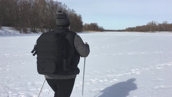 Active an Elderly Woman Engaged in Nordic Walking with Sticks in the Winter Forest