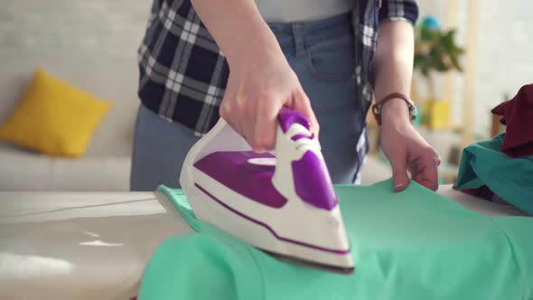 Female Hand Ironing with Iron at Home