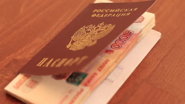 Hands Putting Russian Rubles Into The Passport Of Russian Federation