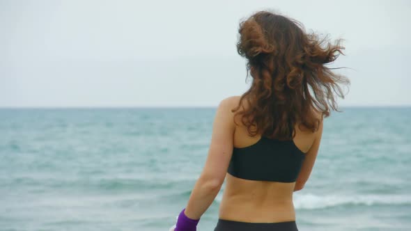 Happy Young Woman Stops to Drink Water After Morning Run, Looking Into Camera