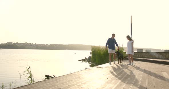 Young European Couple Going Near Lake with Dog