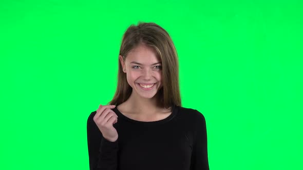 Young Woman Coquettishly Smiling, Waving Hand and Showing Gesture Come Here. Green Screen