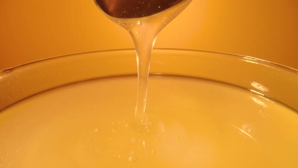 Honey Dripping Pouring From Spoon in Glass