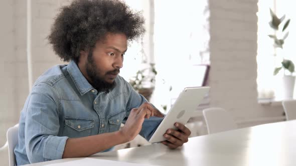 Tense African Man Reacting to Financial Loss While Using Tablet