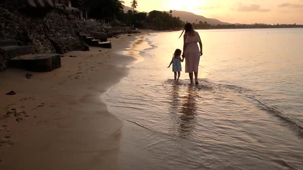 Happy Family on Sea Beach at Resort. Mother and Daughter Playing on the Beach at the Sunset Time
