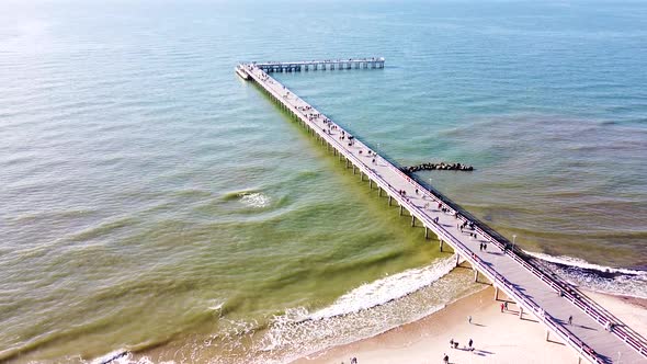 Palanga bridge on sunny day with many people, aerial tilting up view
