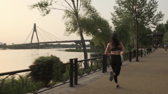 Woman Athlete Running Training Intense Cardio Workout in City Park Against the Sun