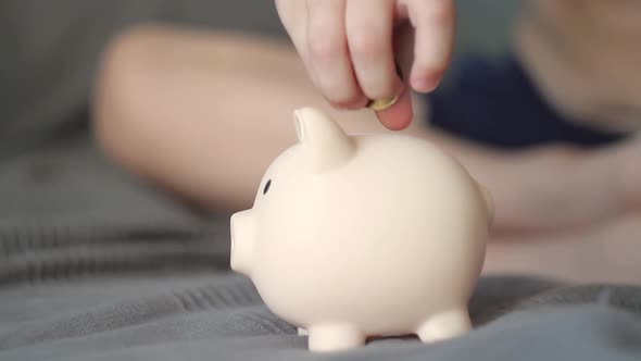 A Happy Child Puts Money in the Piggy Bank