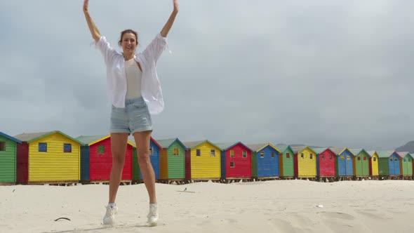 A Girl Dancing on the White Sands of South Africa Near the Colorful Wood Muizenberg Beach Houses